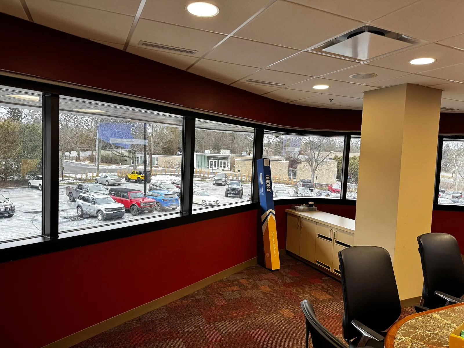 Commercial office with a curved bank of windows treated with professional window film overlooking a Northeast Ohio parking lot