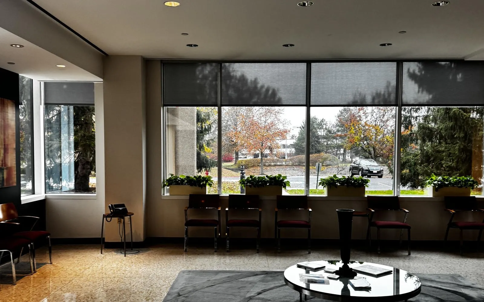 Commercial office lobby with large windows and solar shades overlooking autumn trees in Northeast Ohio